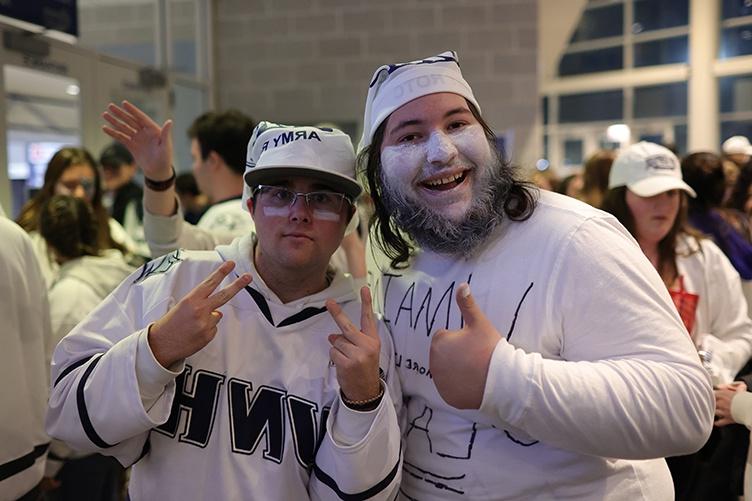 Two male students pose for a photo entering a hockey game